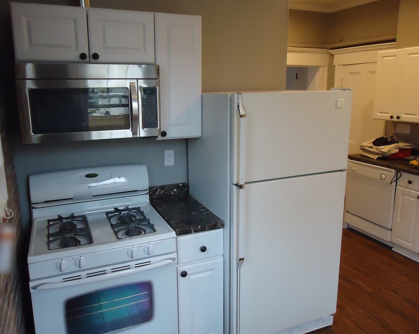 A kitchen with an over-the-range microwave, a gas stove and a white refrigerator