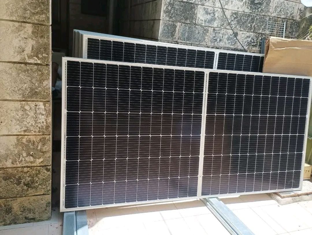 Several new monocrystalline solar panels standing against a wall before installation